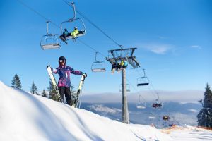 Happy woman is standing with skis on slope