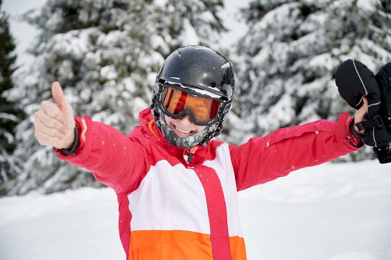 Junge Frau zeigt Daumen hoch, mit Helo und Brille für Sicherheit auf der Piste bei Ski Klante in Winterberg - Skiliftkarussell