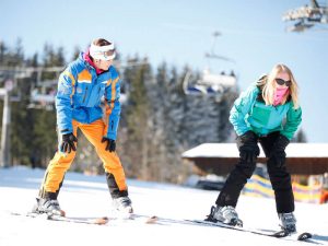 Skileraar met schoolmeisje op ski's op de hellingen