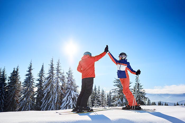 Vrouw en man - high five op ski's op de piste